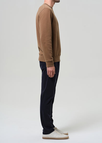 Person wearing a brown sweater and dark pants on a white background