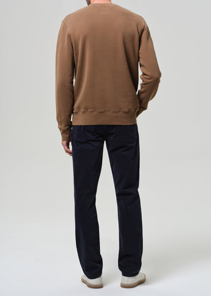 Person wearing a brown sweater and dark pants on a white background
