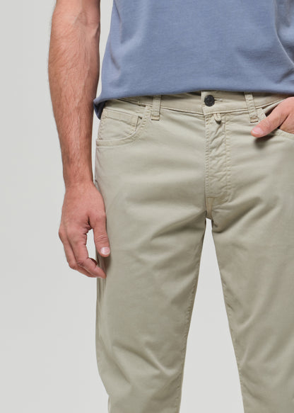 Person wearing a light blue t-shirt and light green pants on a grey background