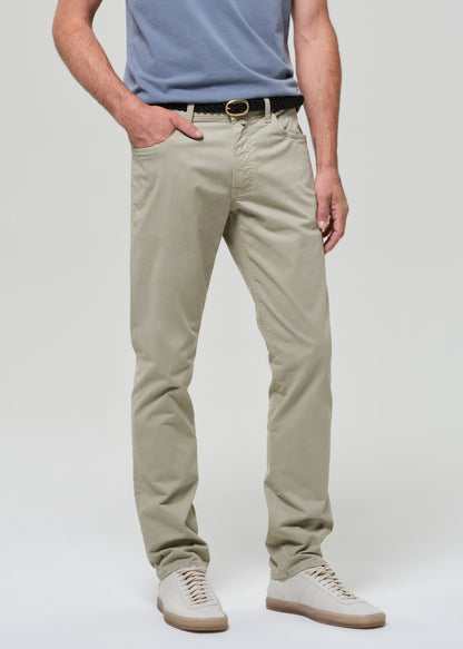 Person wearing a light blue t-shirt and light green pants on a grey background