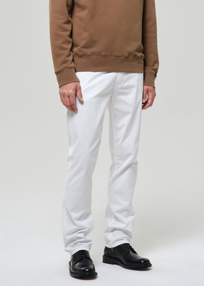 Person wearing a brown sweatshirt and white pants on a plain background