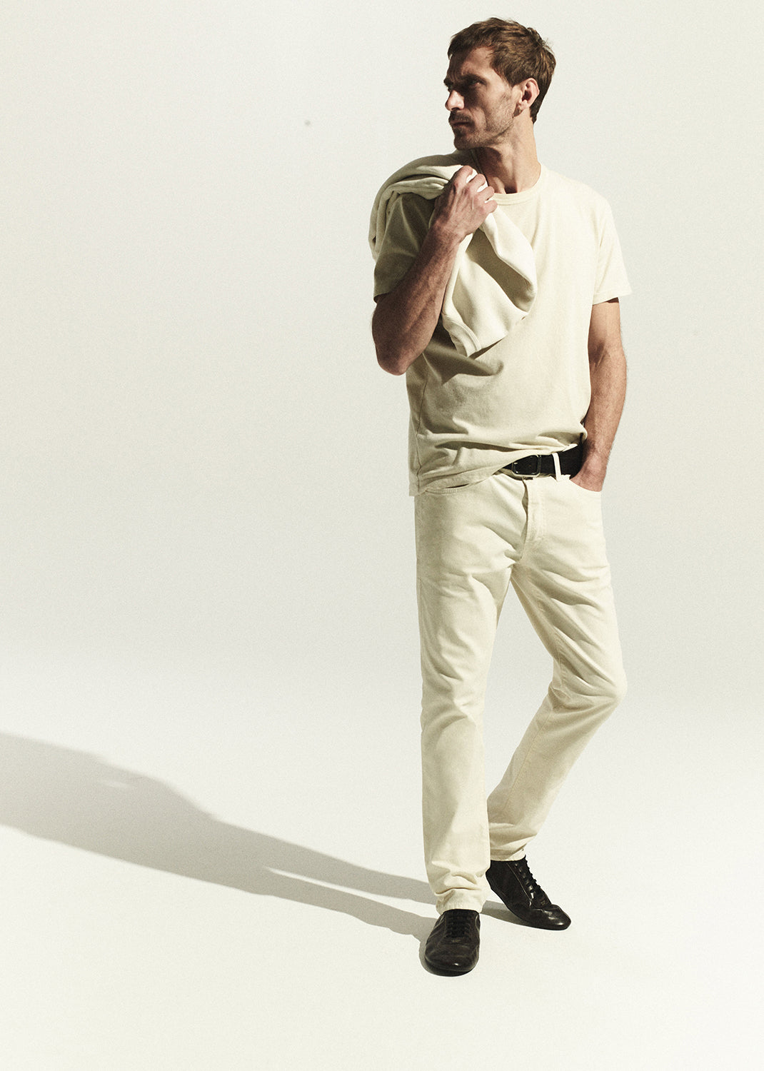 Man wearing a light-colored outfit with a plain background