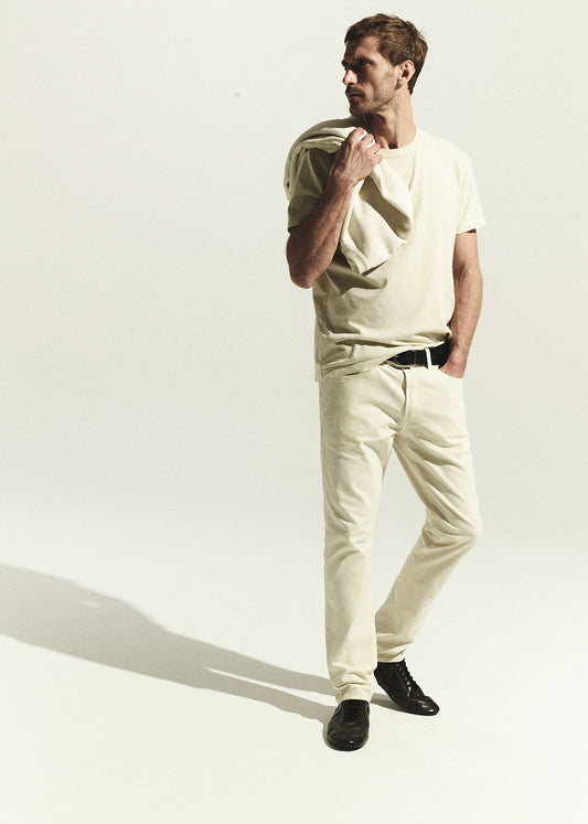 Man wearing a light-colored outfit with a plain background