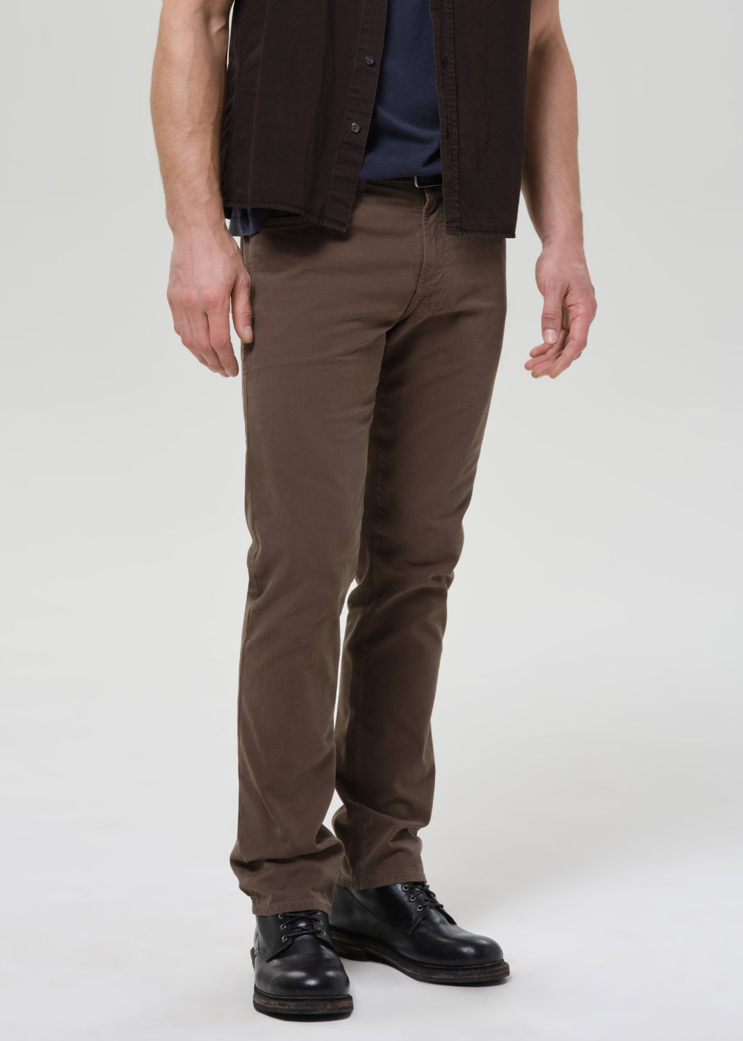 Person wearing brown pants and a dark jacket on a grey background