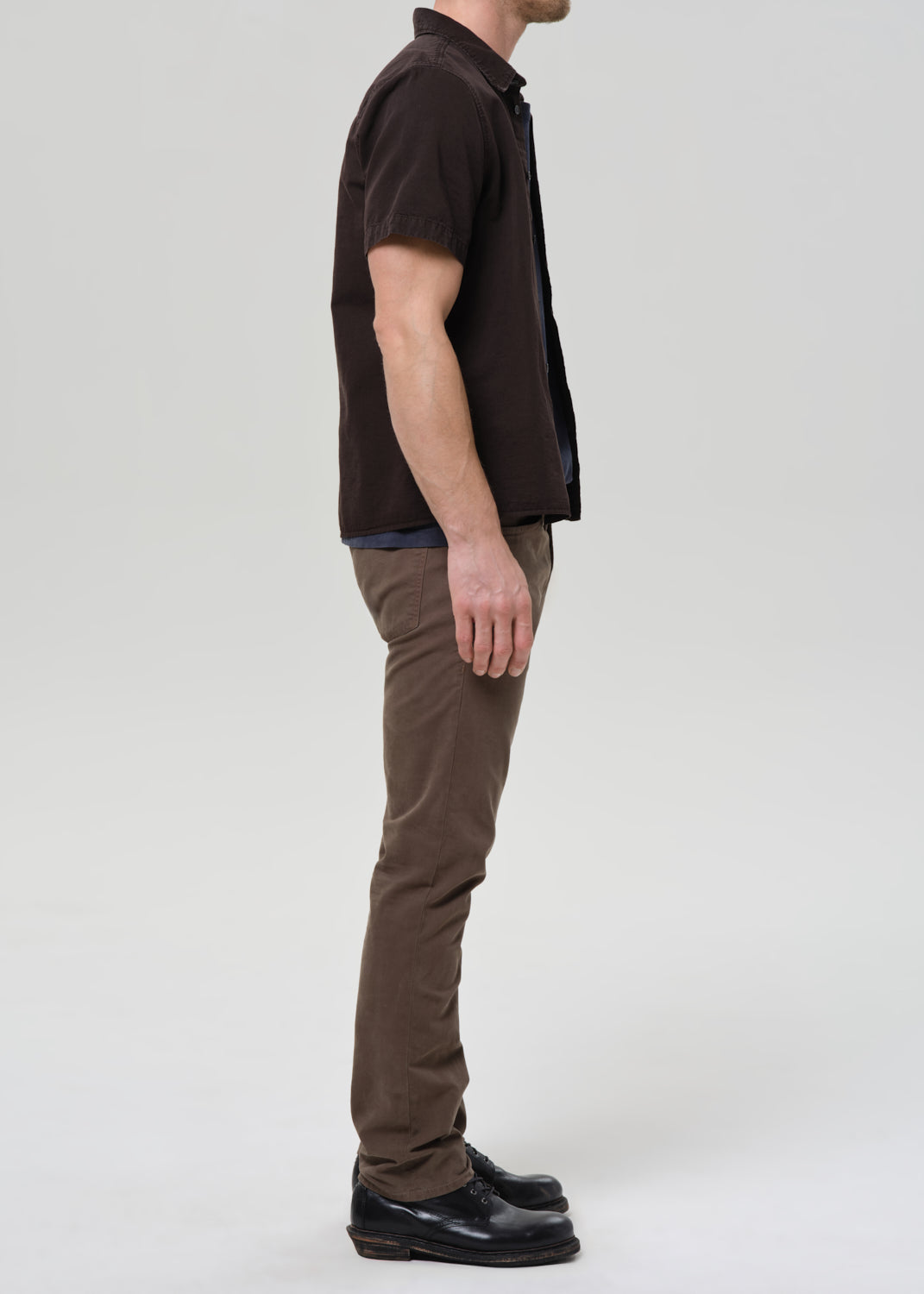 Man wearing a brown shirt and brown pants on a grey background
