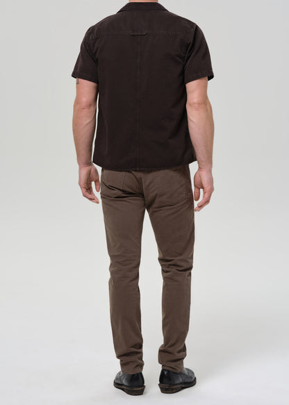Person wearing a black shirt and brown pants on a grey background