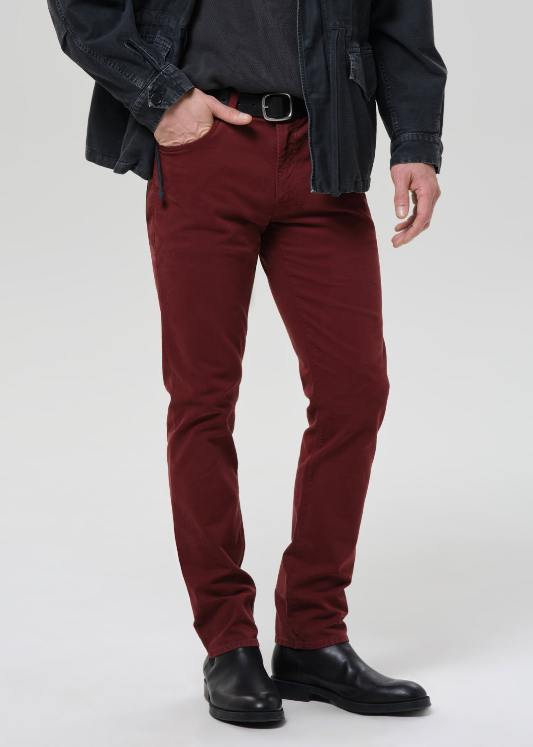 Person wearing maroon pants with a grey background