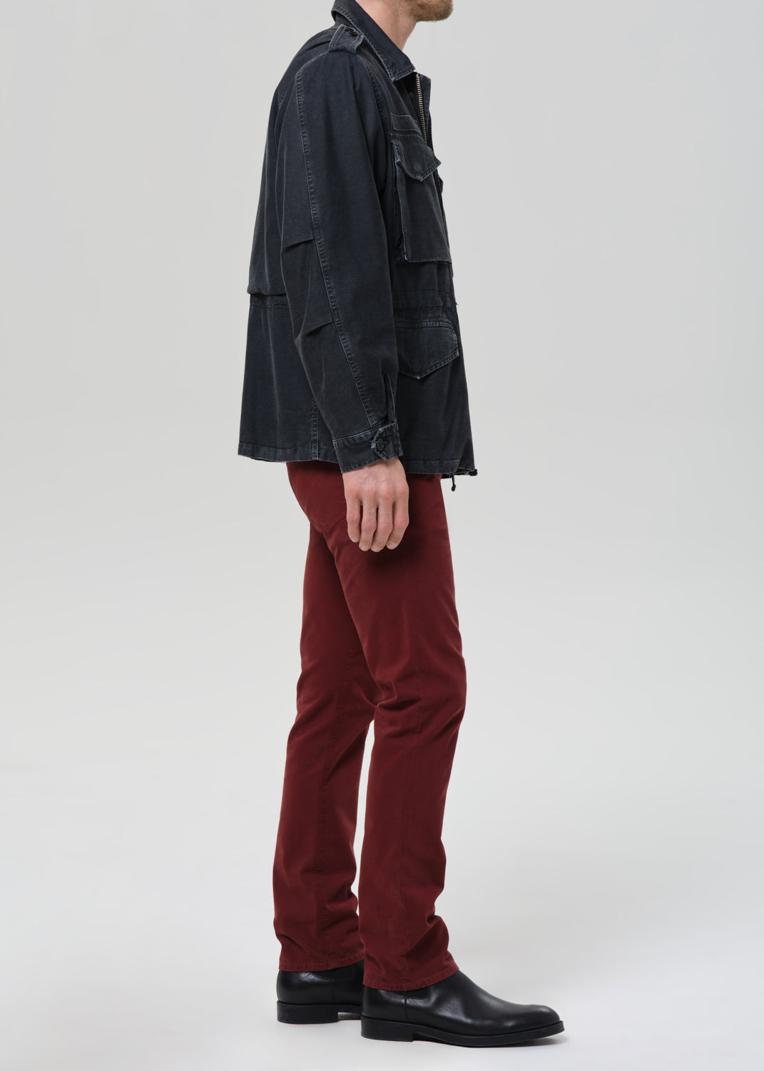 Person wearing a dark jacket and red pants on a grey background