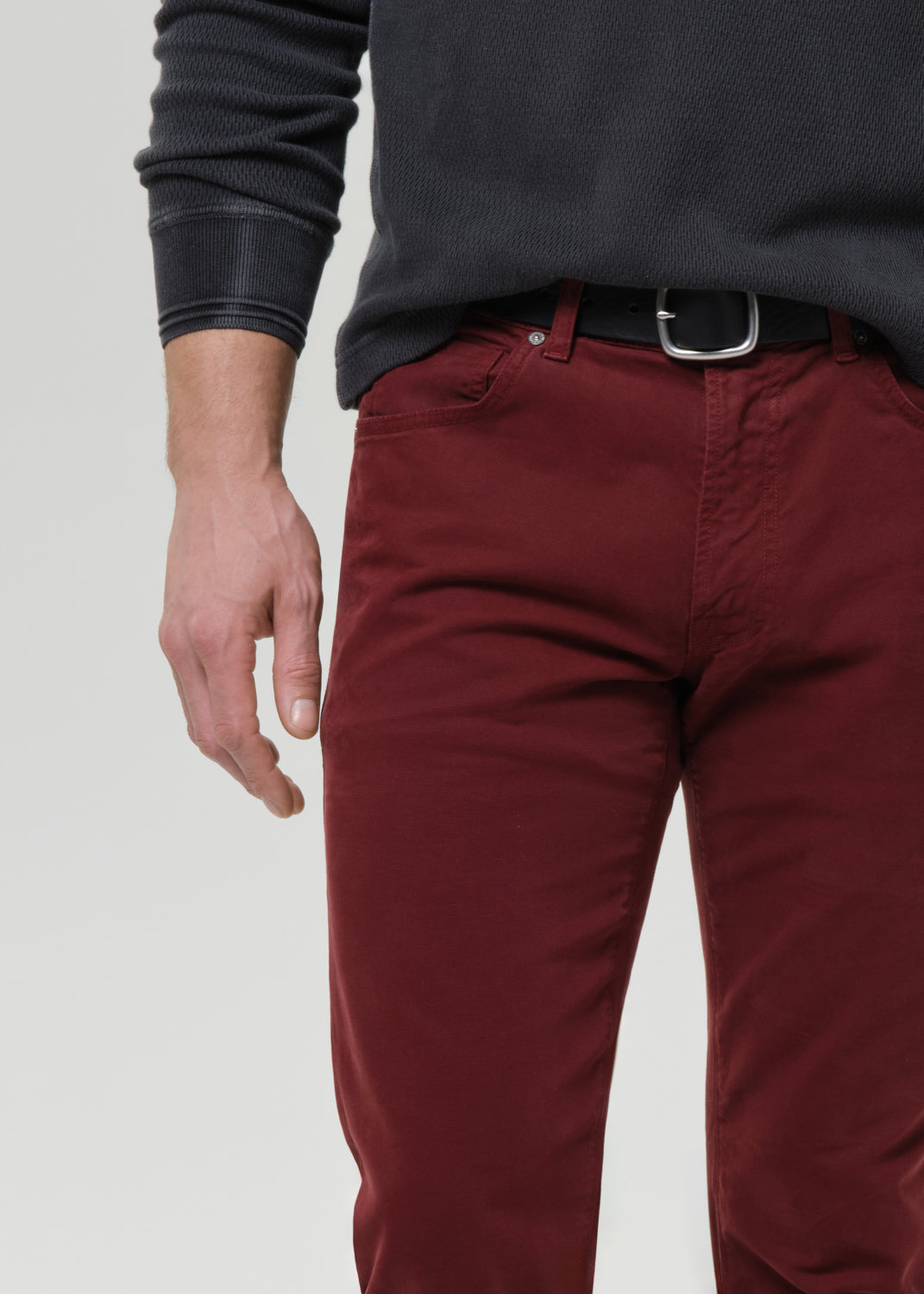 Person wearing maroon pants and a dark shirt on a grey background