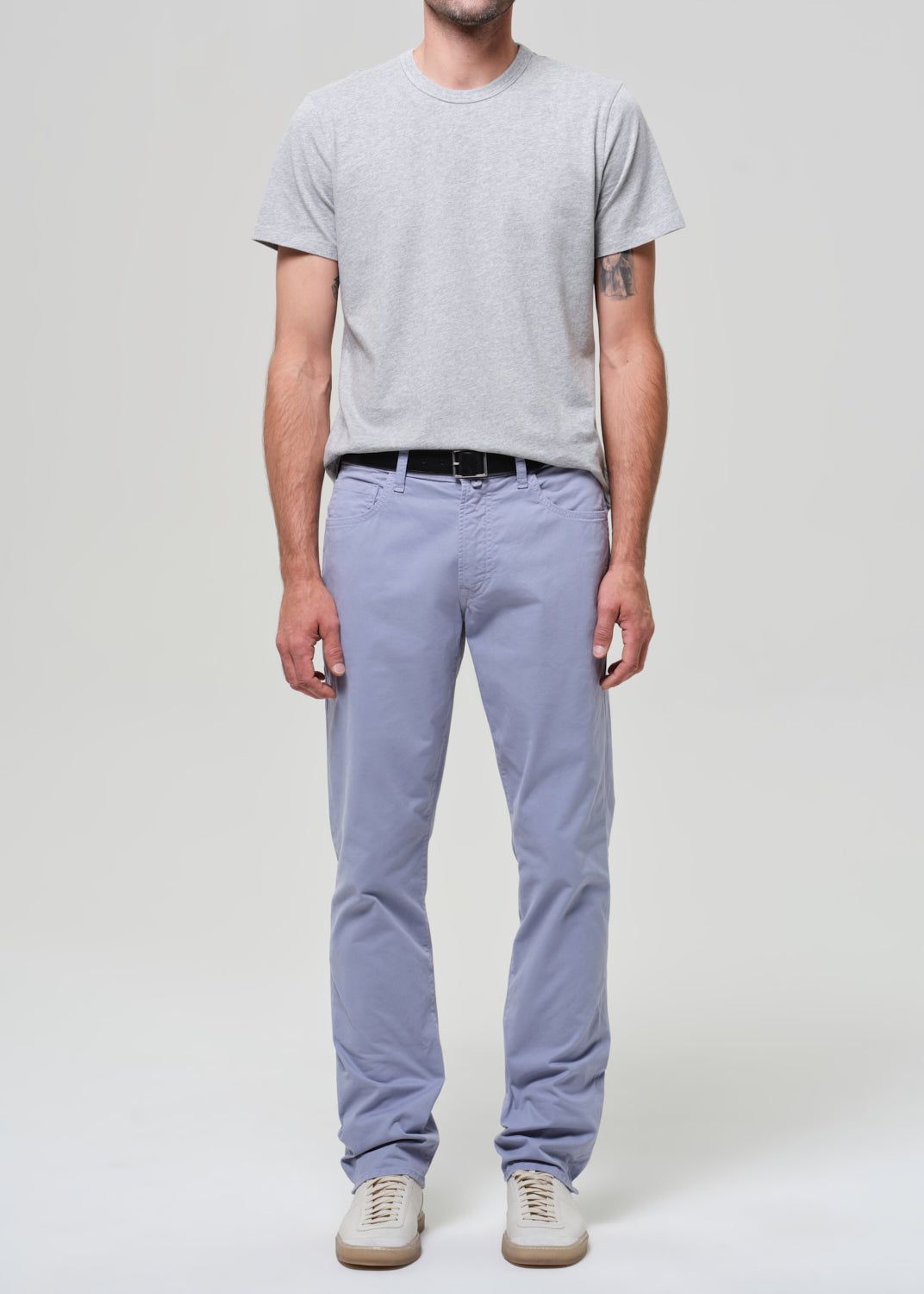 Person wearing a gray t-shirt and light blue pants on a plain background