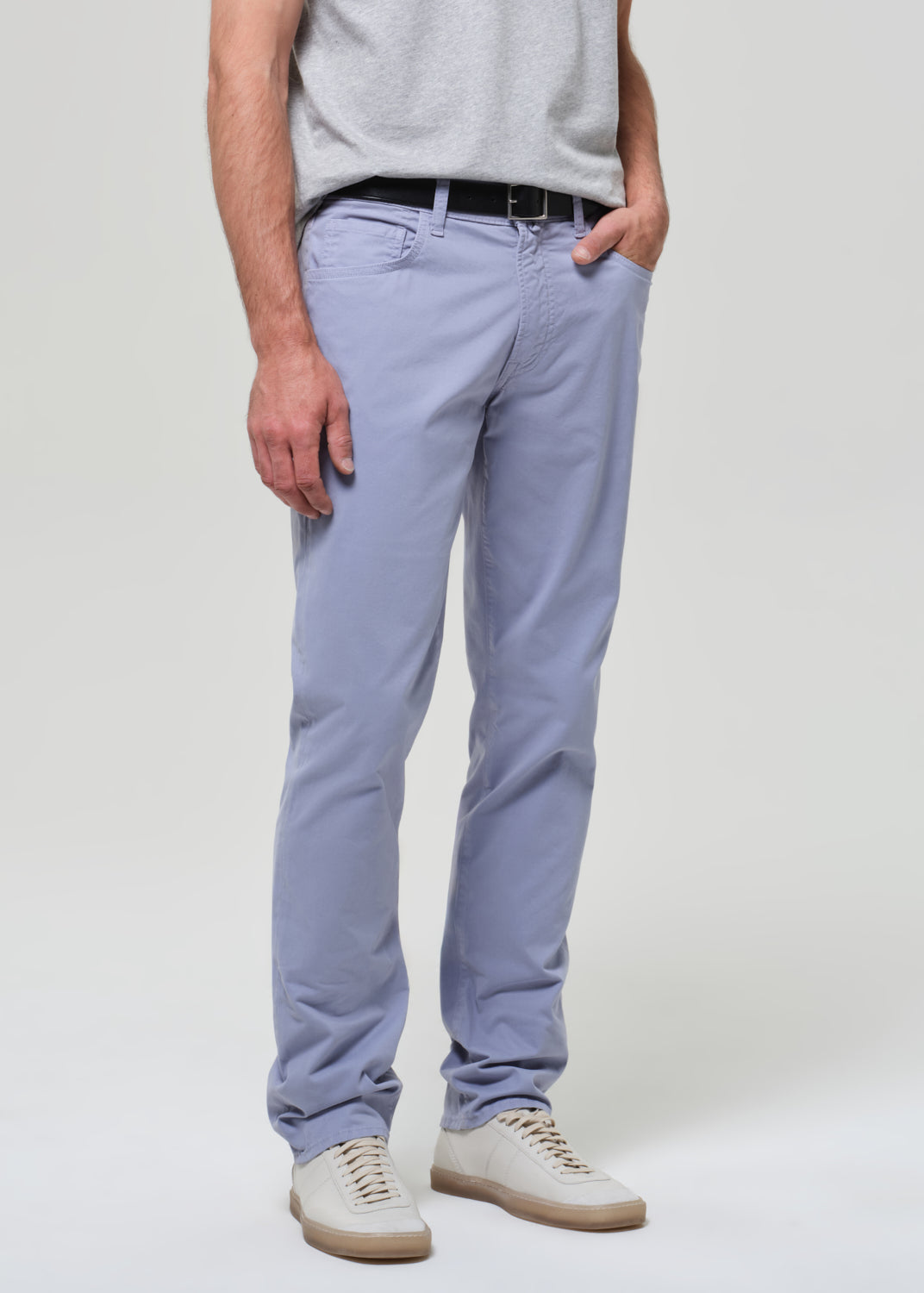 Person wearing a gray t-shirt and light blue pants on a plain background