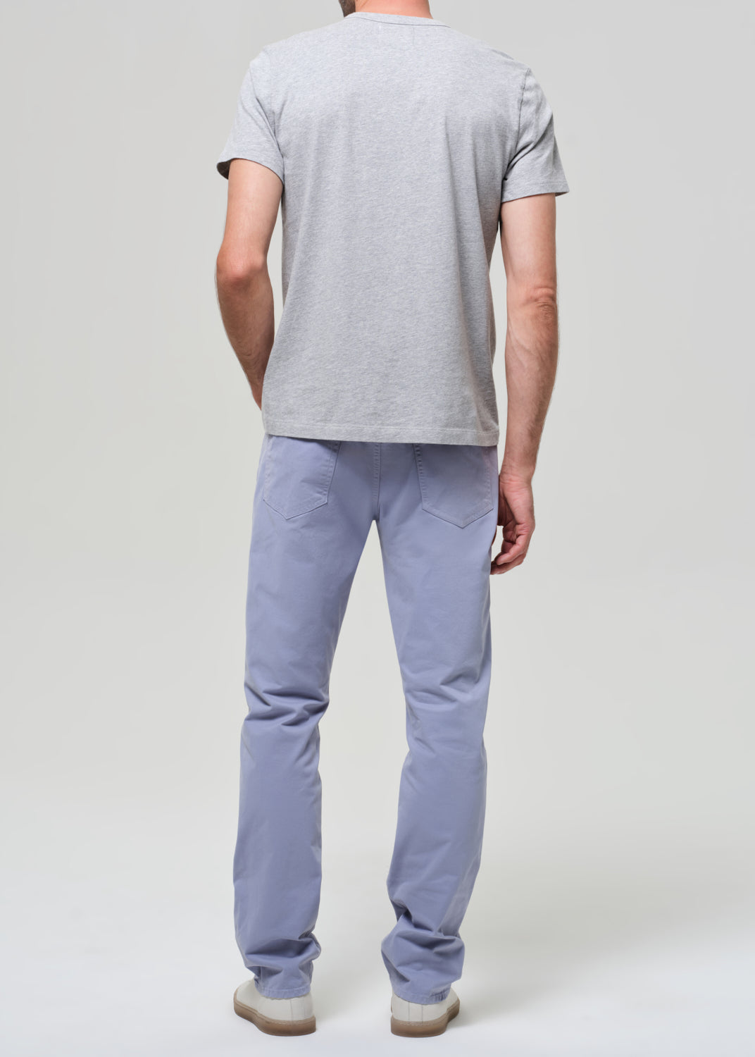 Person wearing a gray t-shirt and light blue pants on a plain background