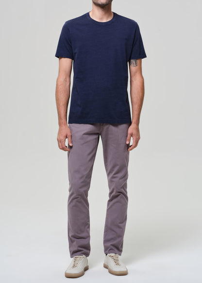 Person wearing a navy t-shirt and grey pants on a grey background