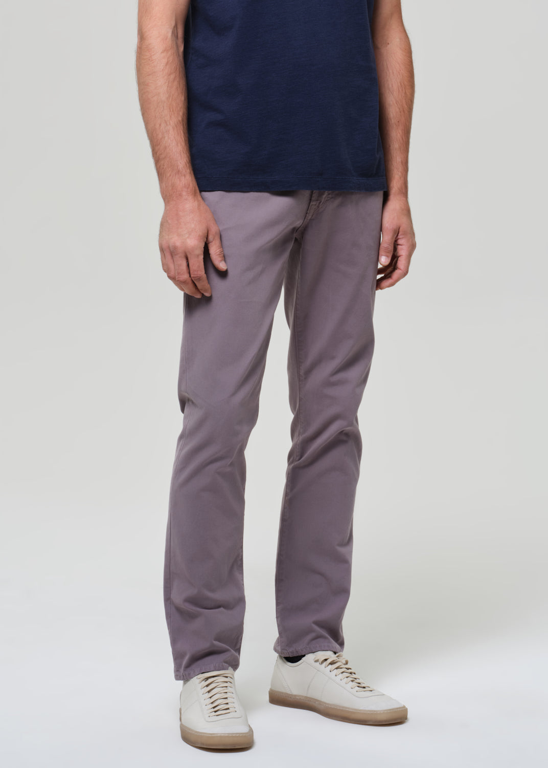 Person wearing a navy t-shirt and grey pants on a grey background