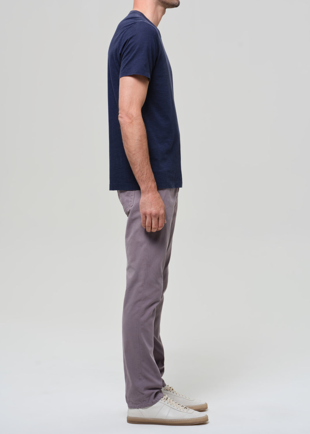 Person wearing a navy t-shirt and grey pants on a grey background