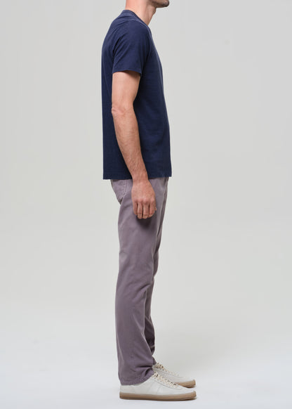 Person wearing a navy t-shirt and grey pants on a grey background