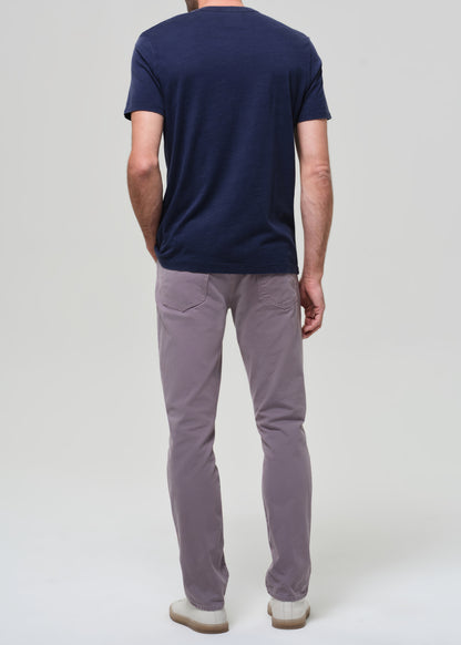 Person wearing a navy t-shirt and grey pants on a grey background