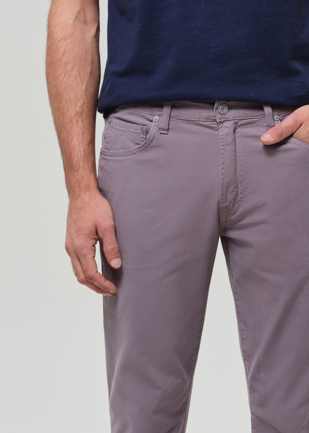 Person wearing a navy t-shirt and grey pants on a grey background