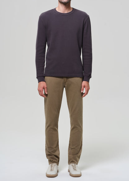 Person wearing a dark long-sleeve shirt and beige pants on a grey background