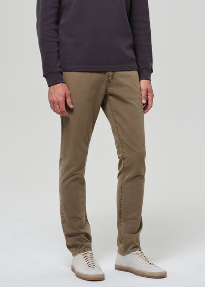 Person wearing a dark long-sleeve shirt and beige pants on a grey background