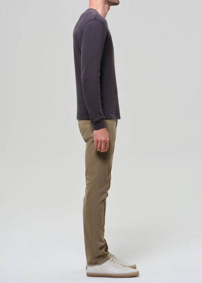 Person wearing a dark long-sleeve shirt and beige pants on a grey background