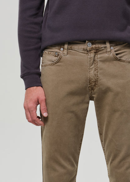 Person wearing a dark long-sleeve shirt and beige pants on a grey background