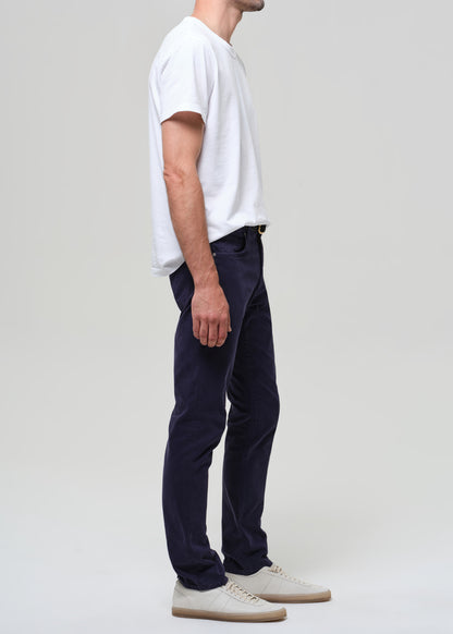 Man wearing a white t-shirt and navy pants on a plain background