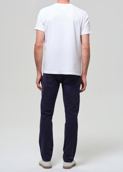 Man wearing a white t-shirt and navy pants on a plain background