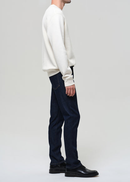 Person wearing a white sweater and dark blue pants on a plain background