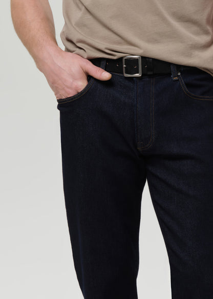 Person wearing dark jeans and a beige shirt with a grey background