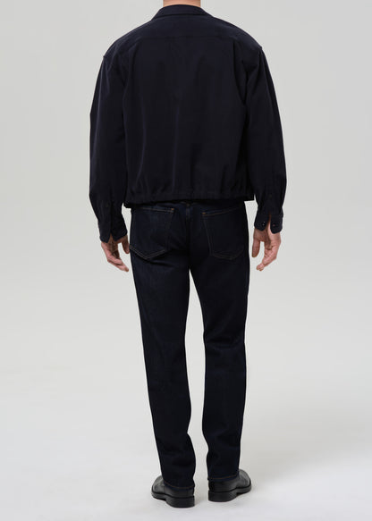 Person wearing a black jacket and pants on a grey background