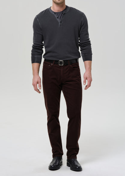 Man wearing a dark gray sweater and brown pants on a grey background
