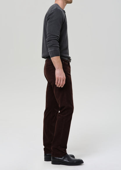 Person wearing a gray sweater and brown pants on a grey background