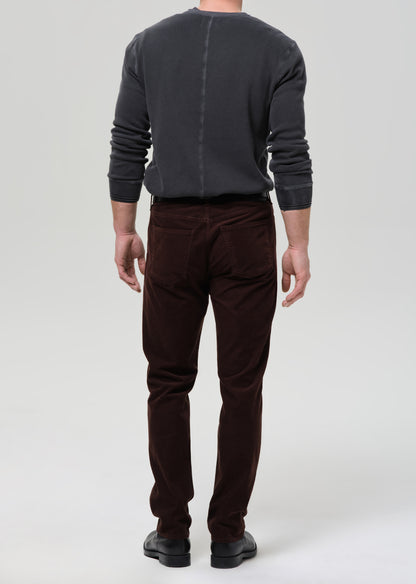 Person wearing a dark gray sweater and brown pants on a grey background