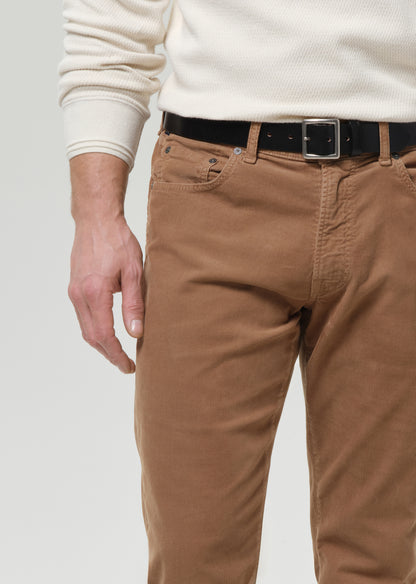 Brown pants worn with a white sweater on a grey background