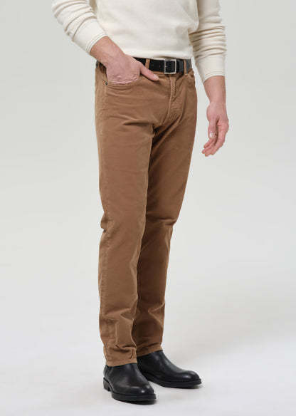 Person wearing brown pants and a white sweater on a grey background