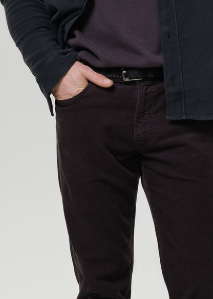 Person wearing dark pants and a jacket on a grey background