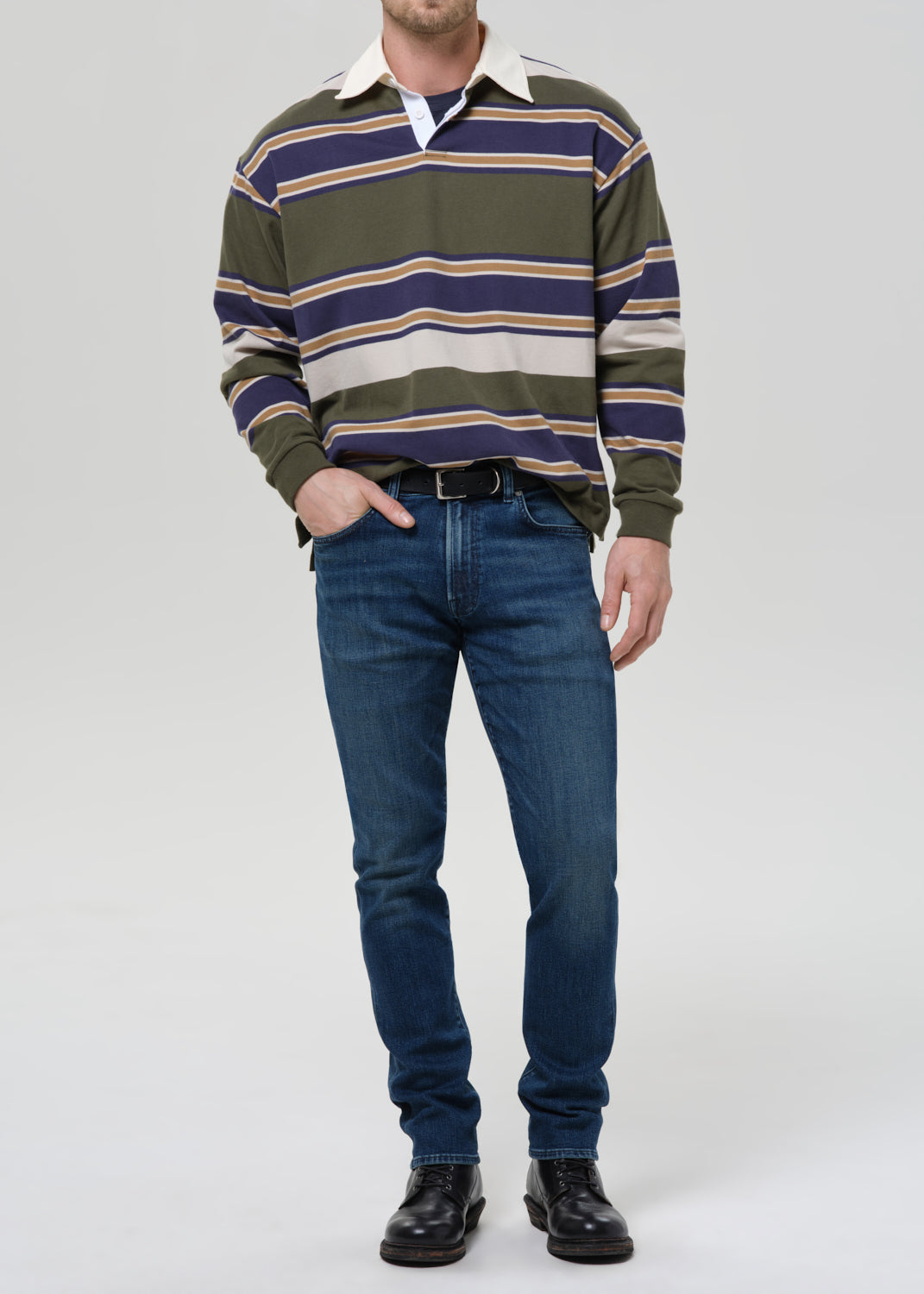 Person wearing a striped sweater and blue jeans on a grey background