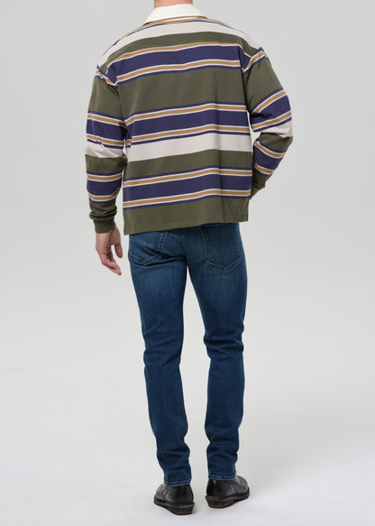 Person wearing a striped sweater and blue jeans on a grey background