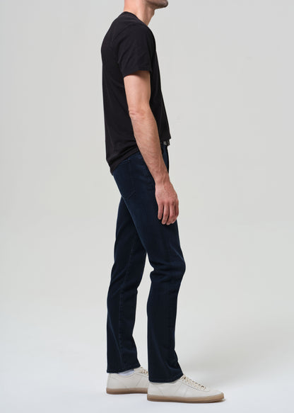 Person wearing a black t-shirt and dark blue jeans on a grey background