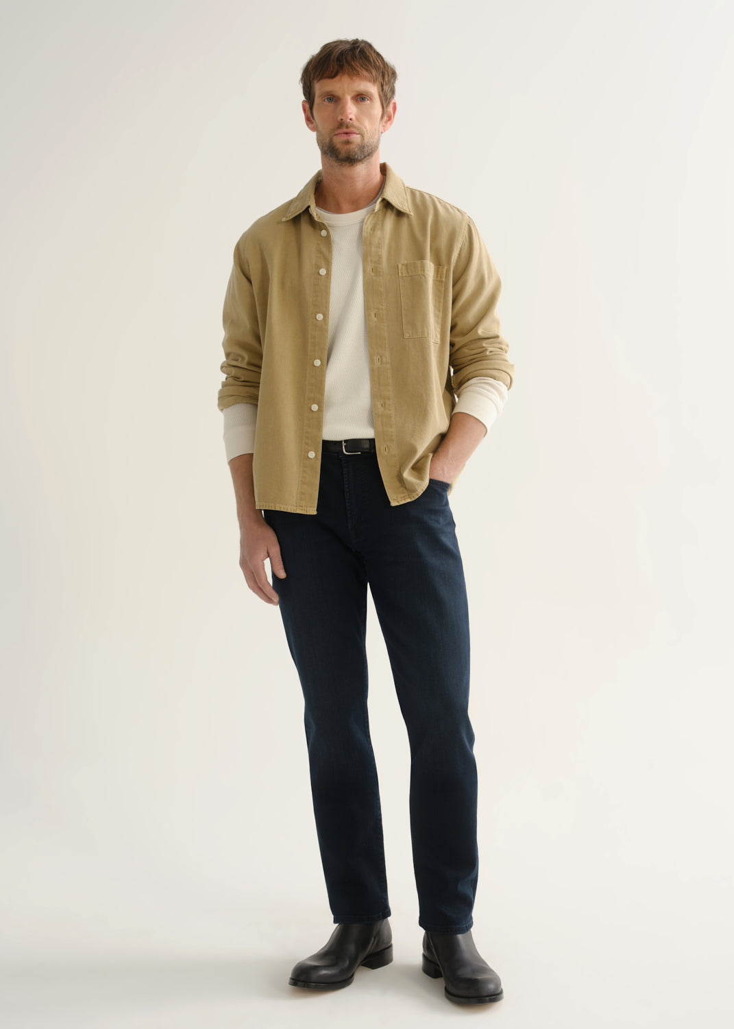 Person wearing tan button-down shirt and dark indigo jeans front