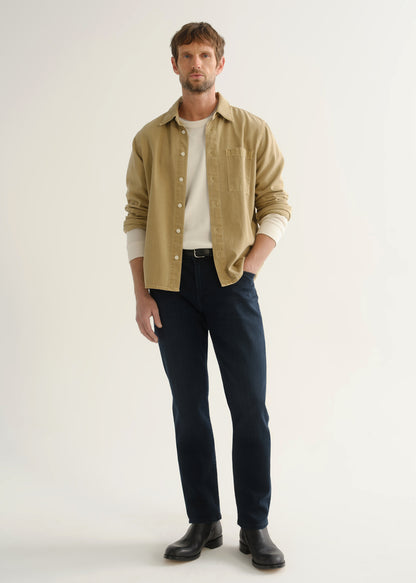 Person wearing tan button-down shirt and dark indigo jeans front