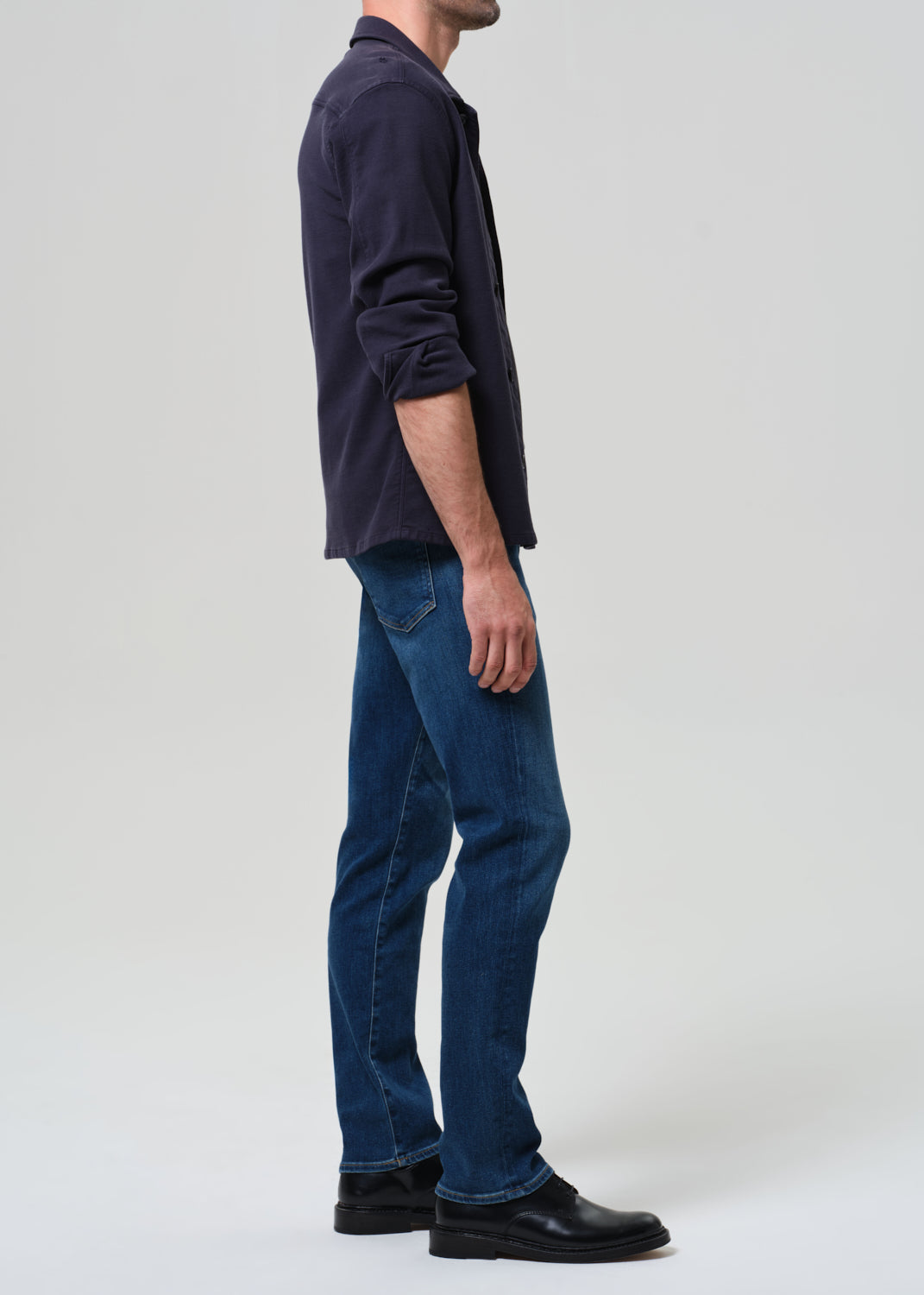 Person wearing a dark shirt and blue jeans on a grey background