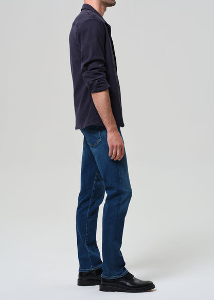 Person wearing a dark shirt and blue jeans on a grey background