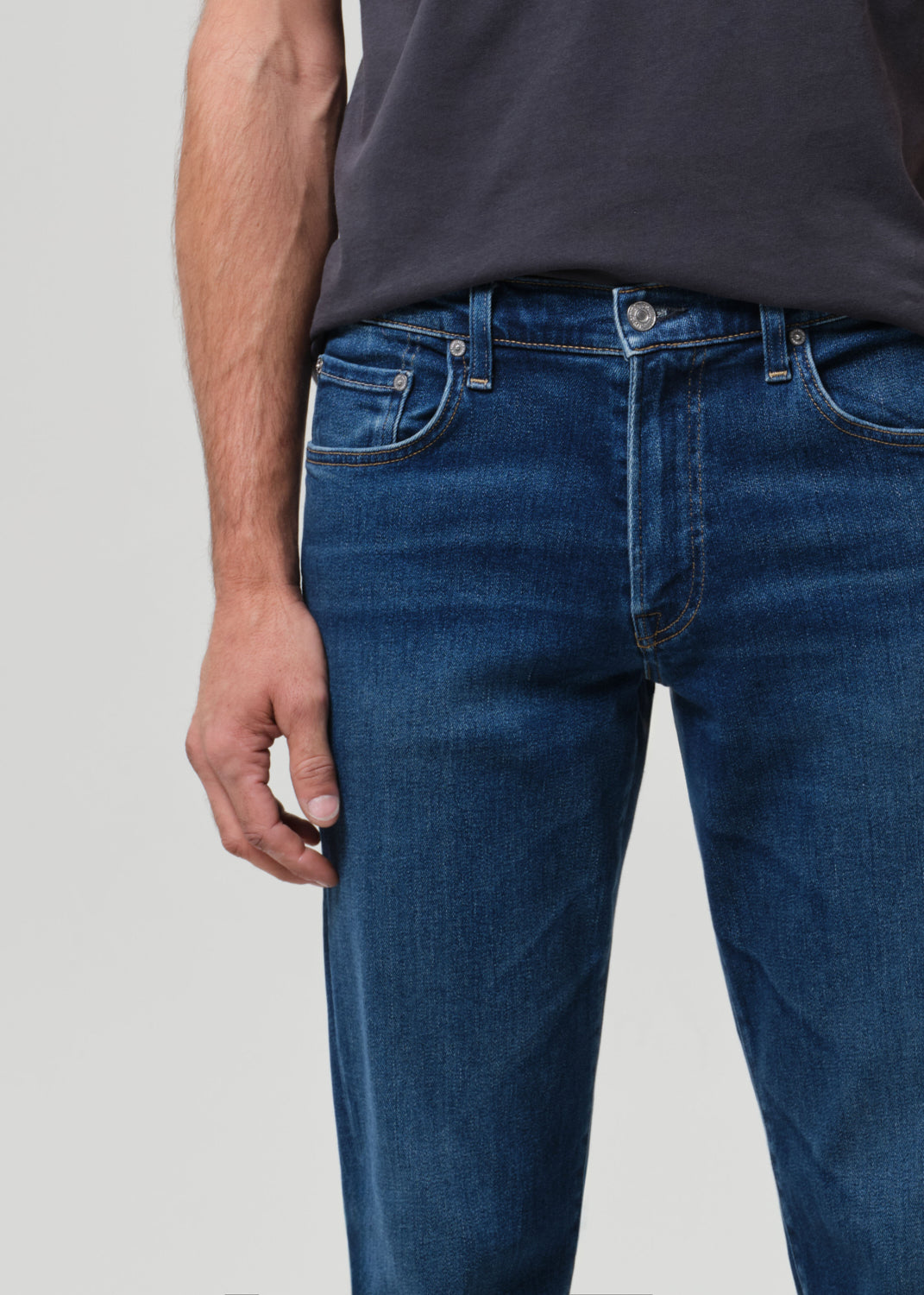 Person wearing blue jeans and a dark shirt on a light gray background