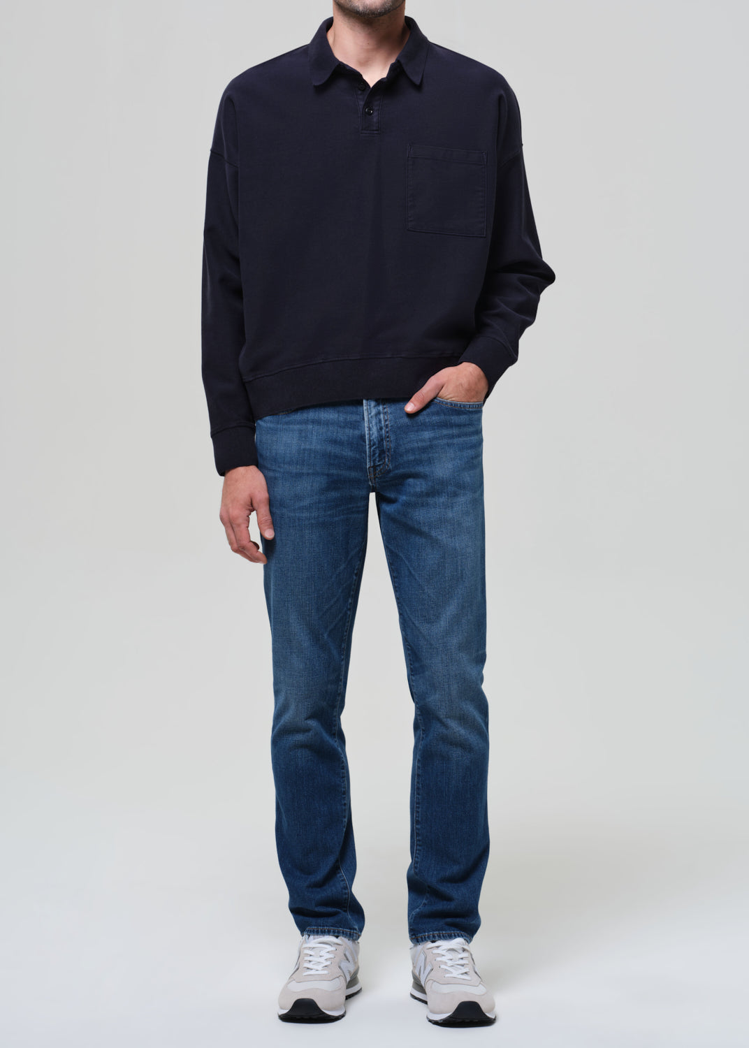 Person wearing a navy sweater and blue jeans on a plain background