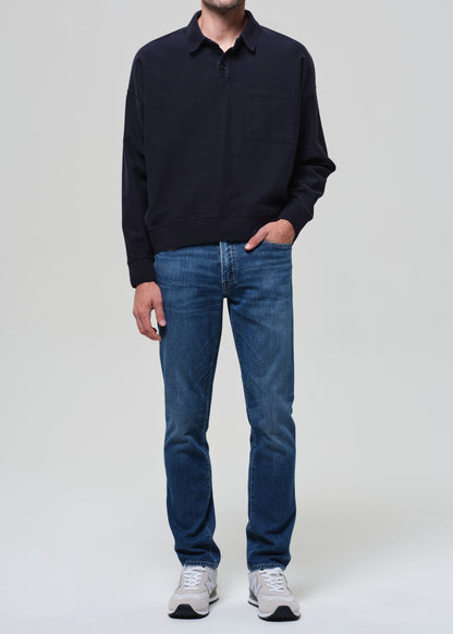 Person wearing a navy sweater and blue jeans on a plain background