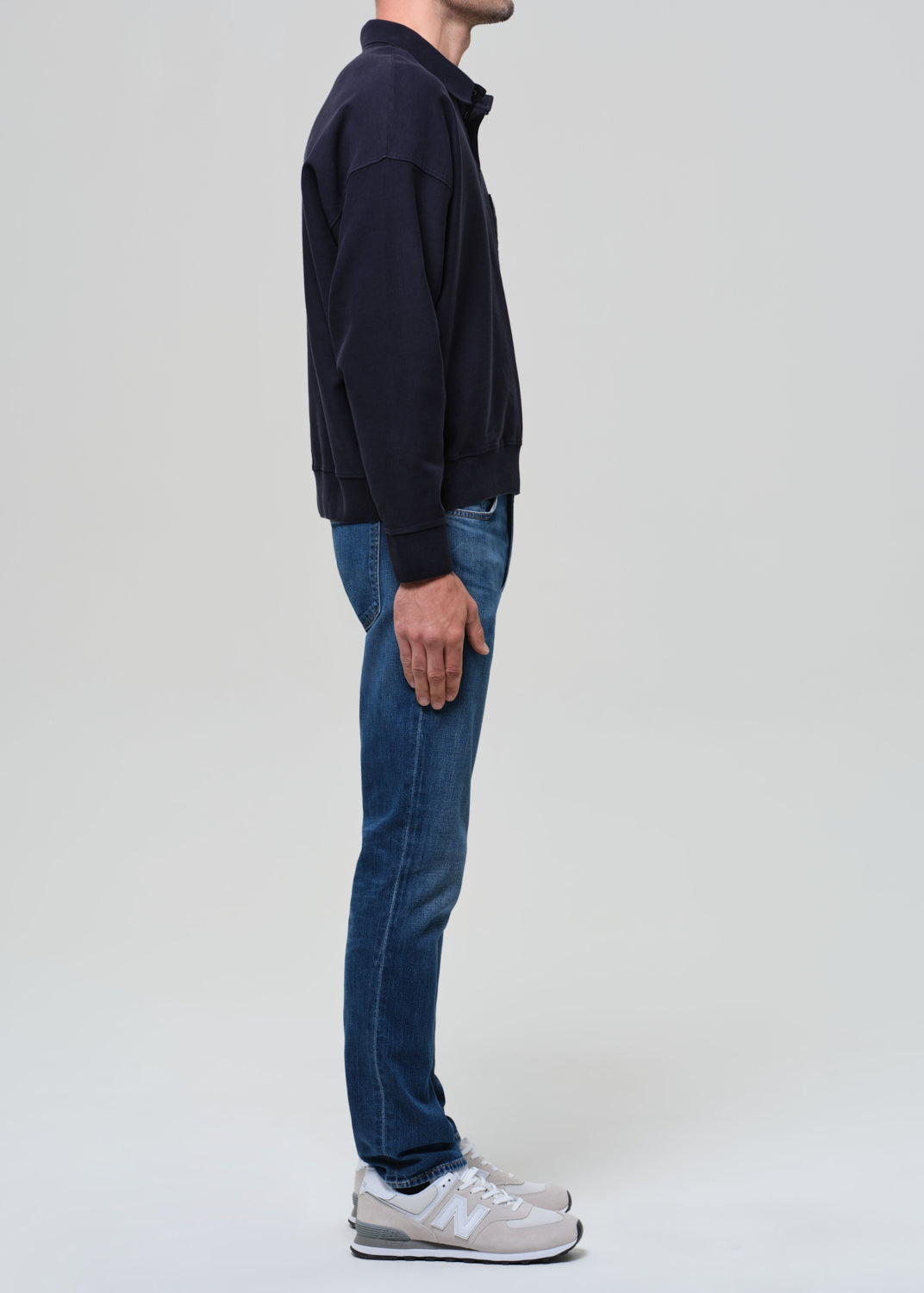 Person wearing a black jacket and blue jeans on a white background