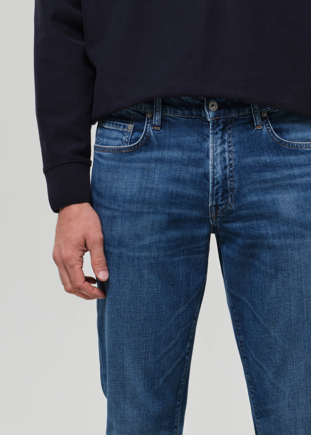 Person wearing blue jeans with a plain background