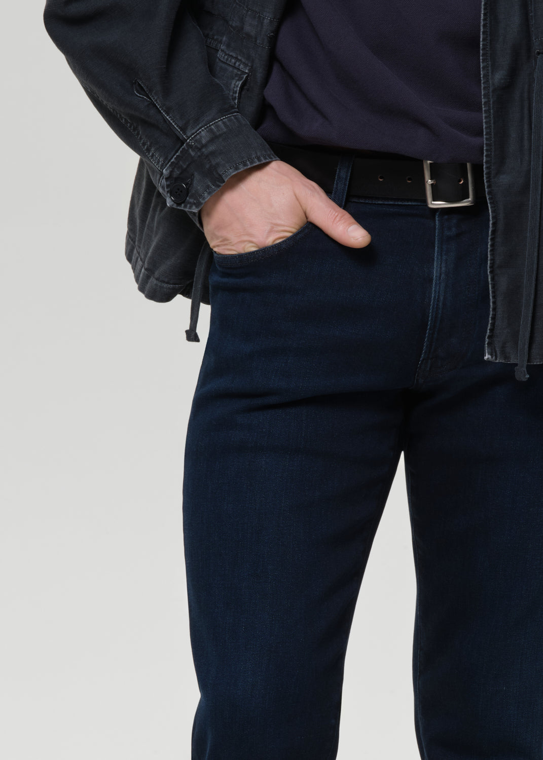 Person wearing dark blue jeans with a grey background